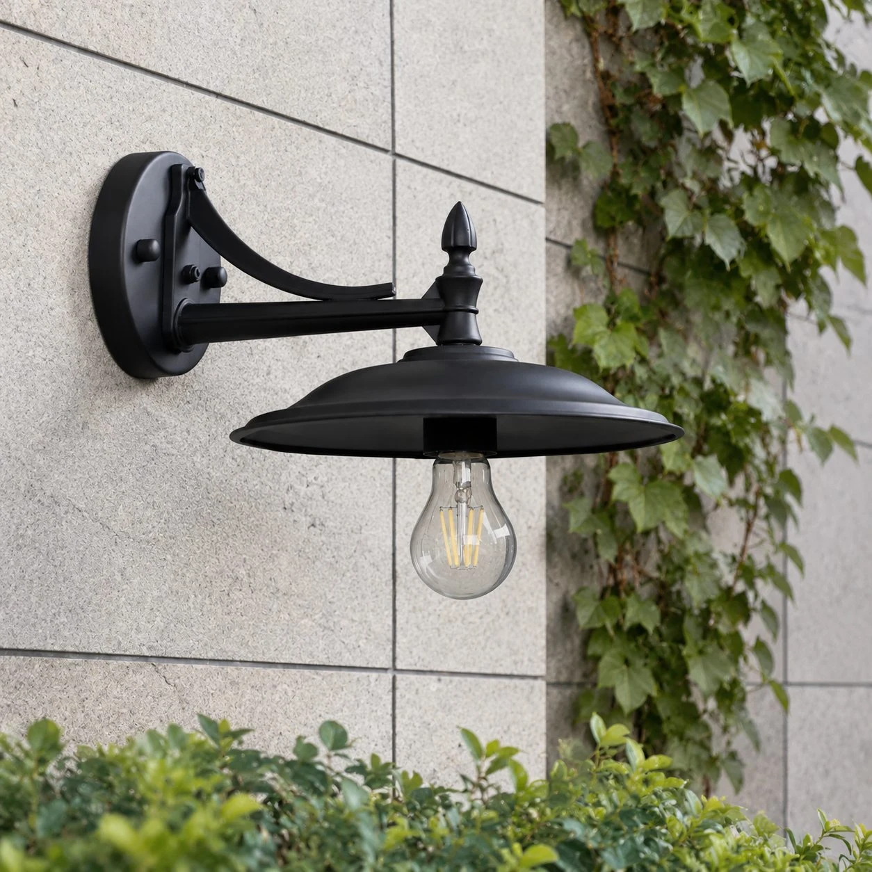 Matte Black wall sconce mounted on a garden wall